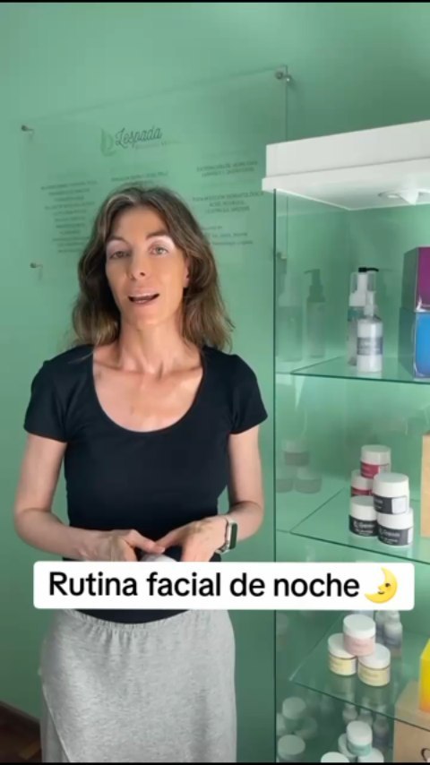 La Dra. Lespada en el consultorio, delante del cartel acrílico con sus tratamientos y la vitrina de dermocosmética